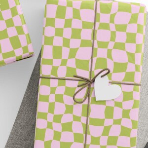 May include: Several wrapped gifts with a pink and green checkered pattern. Each package is tied with twine and a white paper tag in the shape of a star or heart. A ball of twine and scissors are also visible.