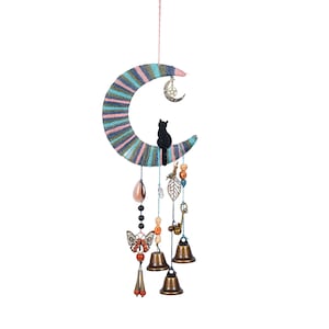 以下が含まれることがあります： カラフルな糸、ビーズ、ベルで飾られた、黒い猫のシルエットがついた三日月型の風鈴。風鈴には、蝶のチャーム、鍵のチャーム、葉っぱのチャームが付いています。