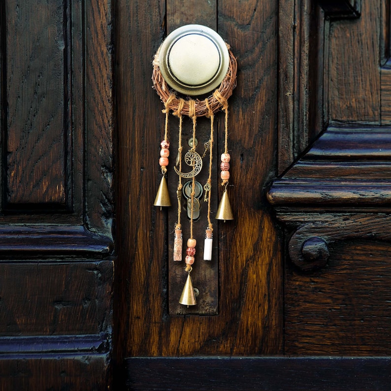 May include: A wooden door with a decorative door knocker that resembles a dream catcher with bells and beads hanging from it.