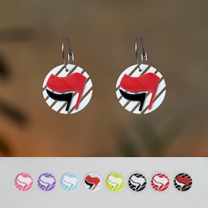 May include: A pair of hoop earrings with a red flag design and a black accent on a white circular base with diagonal stripes. Additional earrings with different colour schemes are displayed below.