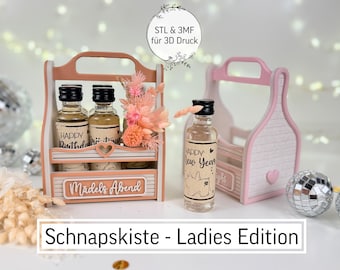 May include: A wooden Schnapskiste, or shot box, in a pink and white color scheme, holding small bottles of liquor. The box has a handle and is decorated with a heart and the words "Happy Birthday" and "Happy New Year". The text "Ladies Edition" is also visible.
