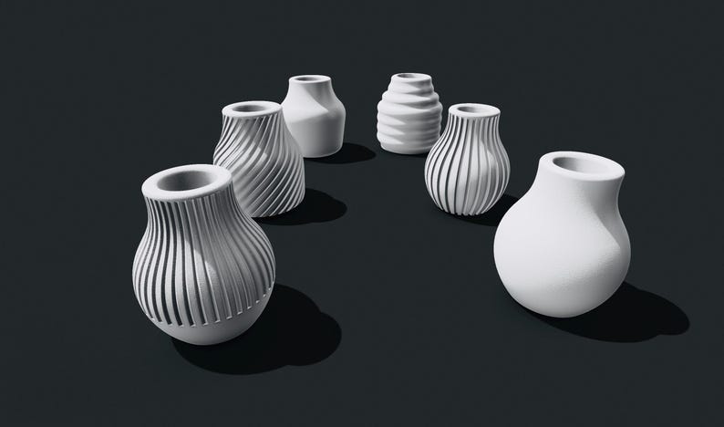 Pu&ograve; includere: Sei vasi in ceramica bianca con diversi disegni testurizzati. I vasi sono disposti a semicerchio su una superficie nera.