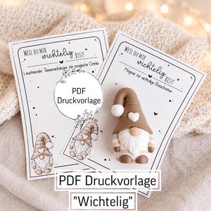 Könnte beinhalten: Zwei weiße rechteckige Karten mit schwarzem Text und Wichtel-Illustrationen. Die linke Karte trägt die Aufschrift 'WEIL DU MIR wichtig BIST!' und 'Leuchtender Tassenanhänger für magische Drinks'. Rechts ist eine braun-weiße Wichtelfigur.