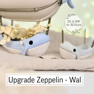 May include: A whimsical, light blue whale-shaped planter with a white belly, holding dried flowers, suspended from a zeppelin. A smaller whale figurine is also present. The text "Upgrade Zeppelin - Wal" is displayed.