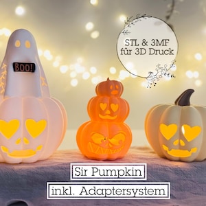 May include: Three Halloween-themed decorative lights. A white ghost-shaped light with "BOO!" text, a stacked orange pumpkin light, and a white pumpkin light with heart-shaped eyes. The lights are on a gray surface.