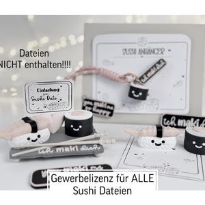 May include: A selection of sushi-themed decorations, featuring miniature sushi rolls, nigiri, and signs. The items are white, black, and pink, with German text. The image includes a card that says "Sushi Date".