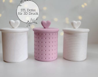 May include: Three white ceramic jars with lids. The lids have a heart-shaped knob. The middle jar is pink and has a pattern of small hearts.