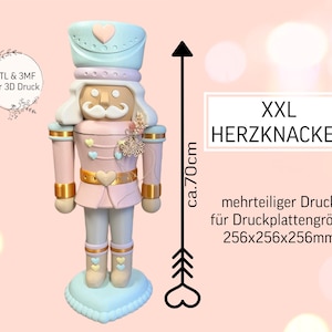 Könnte beinhalten: Pastellfarbene Nussknacker-Figur, ca. 70 cm hoch, mit hellblauem Hut und Sockel, rosa Jacke und goldenen Akzenten. Die Figur hat eine herzförmige Gürtelschnalle und Stiefel. Der Text auf dem Bild lautet "XXL HERZKNACKER".