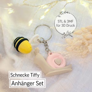 May include: A keychain set featuring a yellow bee charm with black stripes and a snail charm with a pink shell and heart detail. The set includes a metal keyring and the text "Schnecke Tiffy Anhänger Set".