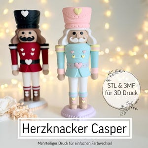 Könnte beinhalten: Zwei dekorative Nussknacker-Figuren. Eine ist rot und schwarz, die andere hellblau und rosa. Die Figuren haben herzförmige Akzente und stehen auf dekorativen Sockeln. Der Text "Herzkknacker Casper" wird angezeigt.