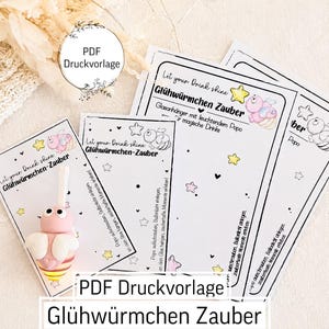 Op de afbeelding: Een set witte papieren kaarten met zwarte tekst en illustraties van vuurvliegjes, sterren en hartjes. De tekst luidt Let your Drink shine Glühwürmchen Zauber. Eén kaart bevat een klein, roze, driedimensionaal vuurvliegje-figuurtje.