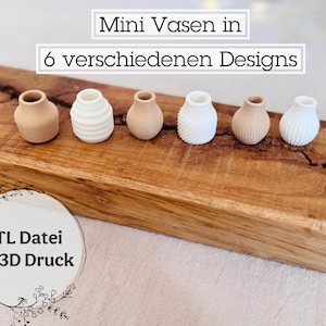 Könnte beinhalten: Sechs Mini-Vasen in verschiedenen Designs, darunter gerippte, glatte und strukturierte Stile. Die Vasen sind auf einer Holzoberfläche angeordnet. Der Text "Mini Vasen in 6 verschiedenen Designs" und "STL Datei für 3D Druck" ist im Bild sichtbar.