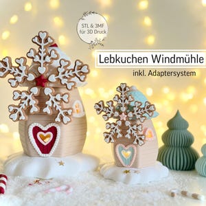 May include: A festive Christmas village scene featuring gingerbread house ornaments with snowflake toppers and heart-shaped accents. The houses sit on a snowy base, with candy canes and small Christmas trees. The text "Lebkuchen Windmühle" is visible.