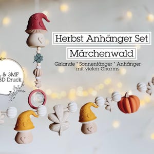 May include: A whimsical garland featuring mushroom, leaf, and pumpkin-shaped charms in shades of orange, yellow, and green. The garland includes the text "Herbst Anhänger Set Märchenwald" and "STL & 3MF für 3D Druck".