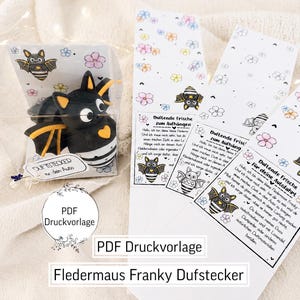 May include: A black and yellow bat-shaped air freshener in a clear plastic box, alongside three white paper strips featuring bat illustrations, floral patterns, and German text including "Duftende Frische zum Aufhängen" and "PDF Druckvorlage".