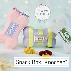 Puede incluir: Tres cajas de aperitivos en forma de hueso en rosa, lavanda y blanco. La caja rosa tiene la palabra "Mampfies", la caja lavanda "Snacks" y la caja blanca "Fein gemacht". Las cajas están junto a golosinas para perros y el texto "Snack Box Knochen".