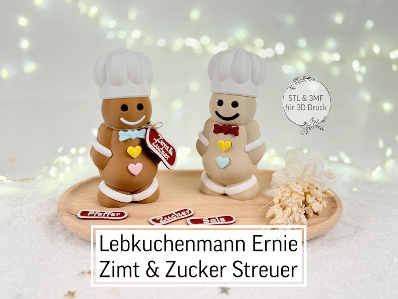 May include: Two gingerbread man-shaped spice shakers, one brown and one beige, each wearing a chef's hat and bow tie. The brown shaker has a blue bow tie and a tag that says "Zimt & Zucker". The beige shaker has a red bow tie. The text "Lebkuchenmann Ernie Zimt & Zucker Streuer" is at the bottom.