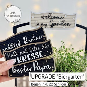Puede incluir: Un letrero decorativo de jardín con el texto "welcome to my Garden". La imagen también muestra tres letreros negros con texto blanco, incluyendo "endlich Rentner" y "Bester Papa". Los letreros se sostienen sobre una pequeña planta.