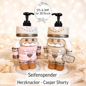 Könnte beinhalten: Zwei Seifenspender in Nussknacker-Optik mit schwarzen Pumpköpfen. Einer ist hellrosa und weiß, der andere beige und weiß. Beide haben herzförmige Knöpfe und Verzierungen. Ein kleines Schild am beigen Spender trägt die Aufschrift Seife. Text: STL & 3MF für 3D Druck, Seifenspender, Herzknacker - Casper Shorty.