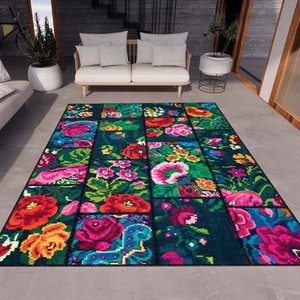 May include: A colourful floral patterned rug with a dark blue background. The rug is made up of individual squares with different floral designs in shades of pink, red, yellow, orange, and green.