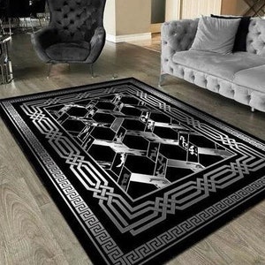Può includere: Tappeto da area nero e argento con un motivo geometrico. Il tappeto ha un bordo con un motivo a chiave greca.