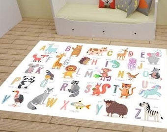 May include: A white alphabet playmat with colorful illustrations of animals and letters. The mat is on a wooden floor in a room with a white couch, a teepee tent, and a small table and chair.