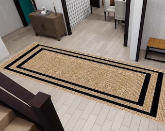 Puede incluir: Una alfombra rectangular de yute con borde negro sobre un suelo de baldosas claras. La alfombra está en una entrada, con una escalera, un banco y objetos decorativos en el fondo. Dimensiones aproximadas: 200 cm x 300 cm.