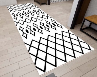 May include: Black and white geometric patterned runner rug with a diamond and wave design. The rug is laid out on a light brown tiled floor.