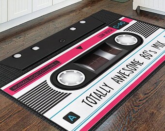 Könnte beinhalten: Ein schwarzer und weißer Kassettenband-Teppich mit rosa Hintergrund. Der Text auf dem Teppich lautet "Totally Awesome 80's Mix FE".