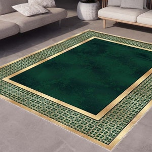 Puede incluir: Una alfombra verde con un borde dorado y un patrón geométrico. La alfombra tiene un aspecto desgastado y es perfecta para añadir un toque de elegancia a cualquier habitación.