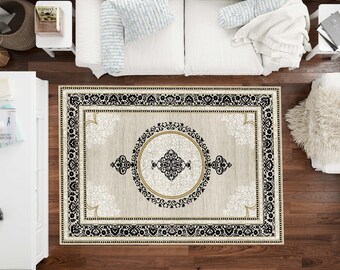 May include: An overhead view of a rectangular area rug with an ornate design. The rug features a beige background with a black and gold border. A central medallion and corner accents add to the rug's decorative appeal. The rug is placed on a dark wood floor.