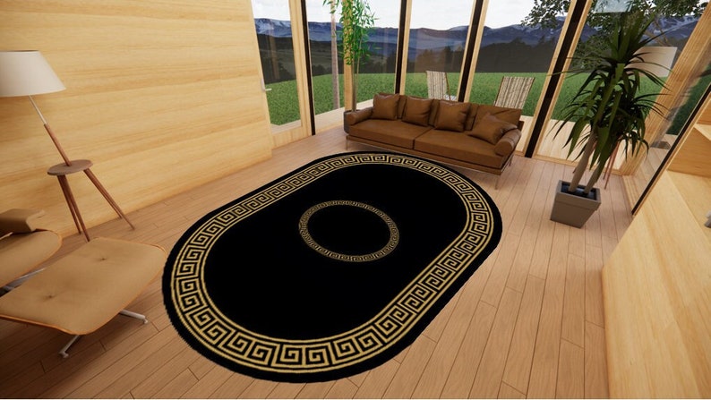 Puede incluir: Una alfombra de forma ovalada con un centro negro s&oacute;lido y un borde ancho decorado con un patr&oacute;n de greca dorada. Un motivo circular m&aacute;s peque&ntilde;o de color dorado con dise&ntilde;o de greca se encuentra centrado en el campo negro.