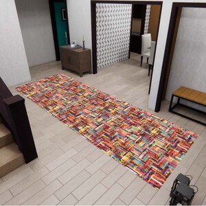May include: A rectangular runner rug featuring a vibrant, multi-colored pattern of stacked books in shades of red, blue, yellow, and orange. The rug is positioned on a light-colored floor in a hallway, displaying a dense, repeating book spine design.