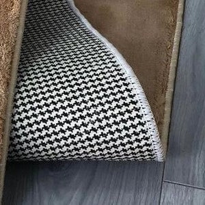 May include: A brown rug with a black and white patterned backing. The rug has a fringed border.