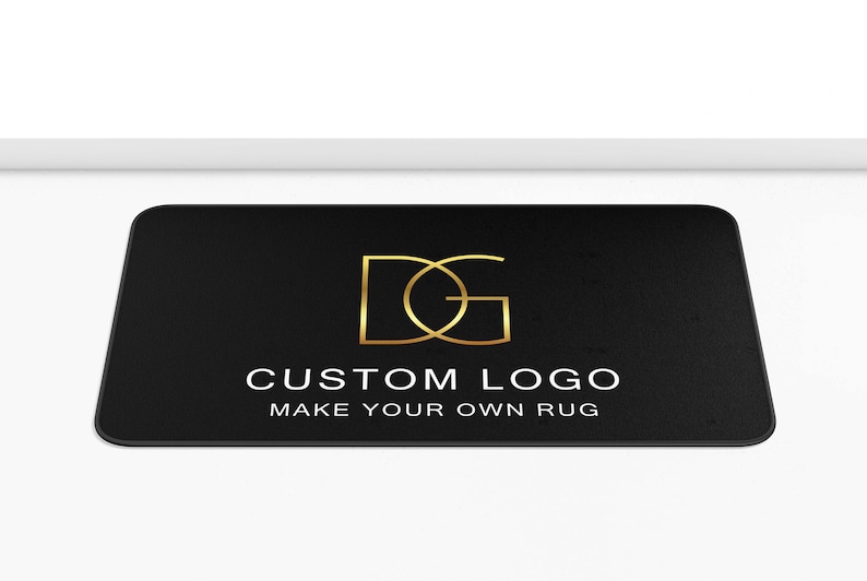 Puede incluir: Felpudo negro con un monograma dorado de las letras "DG" y el texto "CUSTOM LOGO MAKE YOUR OWN RUG".