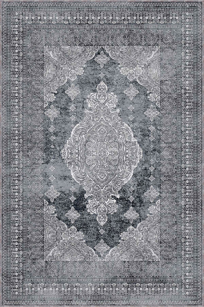 May include: A grey and white patterned rug with a traditional design. The rug features a central medallion with intricate details and a border with repeating motifs.