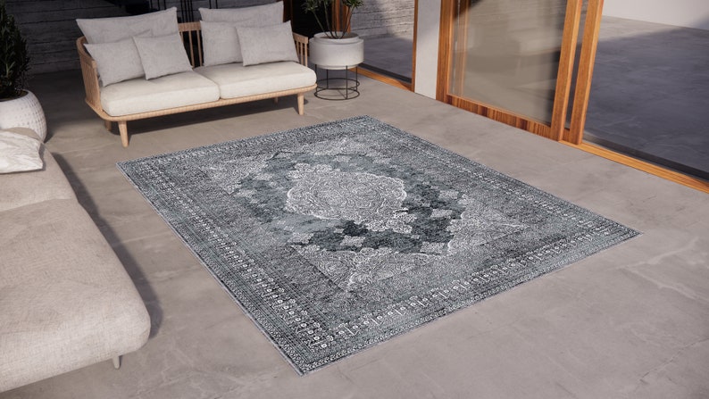 May include: A grey and white patterned rug with a vintage design. The rug is laid out on a concrete floor in a modern living space.