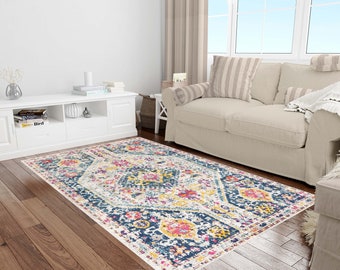 Puede incluir: Una alfombra de color blanco, azul, amarillo, rosa y rojo con un diseño geométrico. La alfombra está sobre un suelo de madera en un salón.