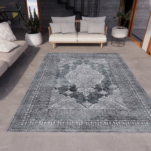 May include: A grey and white patterned rug with a vintage design. The rug is laid out on a concrete floor in a modern living room setting.
