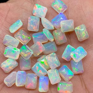 以下が含まれることがあります： 虹色の虹色の光沢を持つ、20個の緩い白いオパール宝石のコレクション。宝石は長方形のエメラルドの形にカットされています。