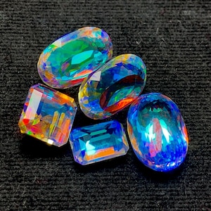 May include: Five iridescent gemstones in various shapes and sizes, including oval, rectangular, and square, with a rainbow of colors, including blue, green, and purple.