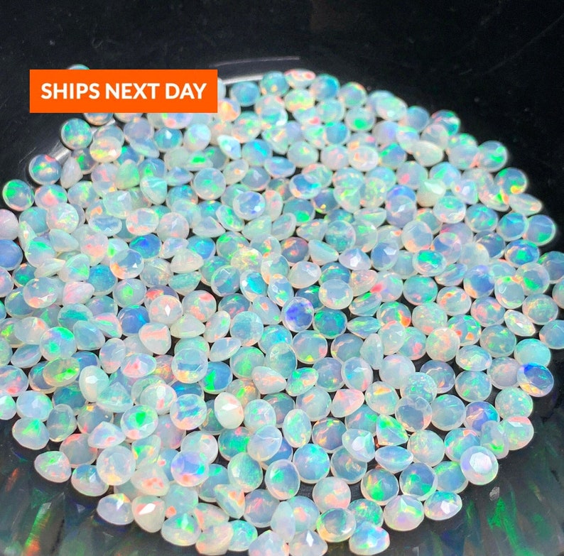May include: A close-up view of a pile of white opal gemstones. The opals are round and have a iridescent sheen.