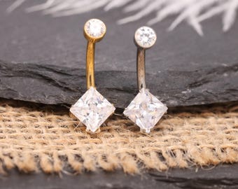Piercing de umbigo 14G quadrado com zircônia cúbica, modelo Cross Back G23, em titânio, ouro e prata. Joia corporal delicada e minimalista.