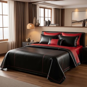Peut inclure: Un ensemble de lit noir et rouge avec un aspect cuir. La literie comprend une housse de couette, des oreillers et des draps. La housse de couette et les taies d'oreiller sont noires avec des détails rouges. Les draps sont rouges.