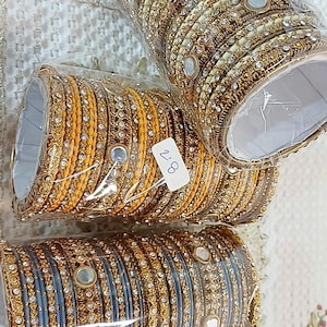 Puede incluir: Tres juegos de brazaletes dorados y plateados con detalles de espejo. Los brazaletes están empaquetados en plástico y etiquetados con el precio "2,88".