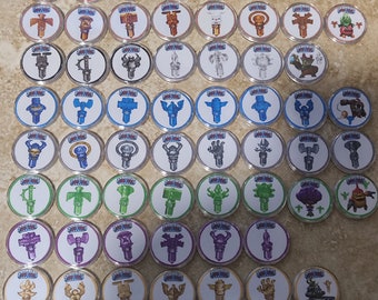 May include: A collection of 50 Skylanders Imaginators character tokens. The tokens are round and feature various characters from the Skylanders video game series. The tokens are arranged in rows and columns on a light brown surface.