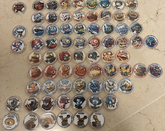 May include: A collection of 50 Skylanders Imaginators character trading cards. The cards are round and feature different characters from the Skylanders video game series. The cards are arranged in rows and columns on a tiled surface.