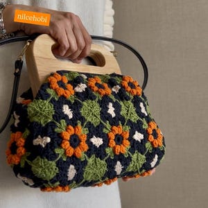 Puede incluir: Bolso de mano de ganchillo con asa de madera. El bolso presenta un estampado floral en naranja, verde, blanco y azul marino. El texto "nilcehobi" es visible en la imagen.