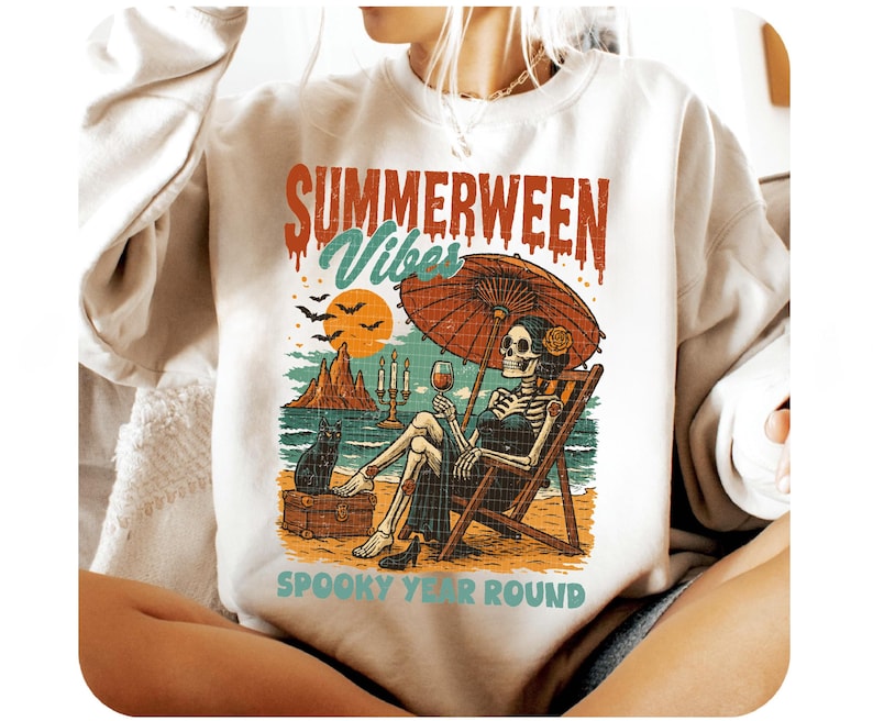 May include: White sweatshirt with a colorful graphic. The graphic features a skeleton relaxing on a beach chair under an umbrella, holding a glass of wine. Text reads "SUMMERWEEN Vibes" and "SPOOKY YEAR ROUND".