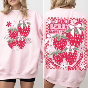 May include: Pink sweatshirt with a graphic of strawberries and the text "Life is Berry Sweet So Choose Happiness" on the back.